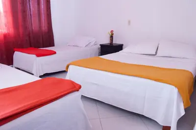 two beds in a room with red curtains at Hotel Recuerdos del Estadio in Medellín