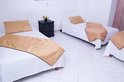 a bedroom with two beds and a tiled floor at Hotel Recuerdos del Estadio in Medellín