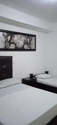 a bedroom with two beds and a picture on the wall at Hotel Recuerdos del Estadio in Medellín