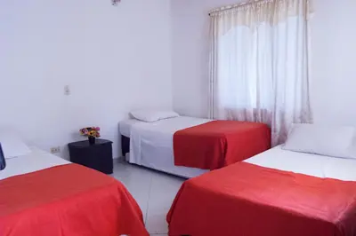 a room with two beds with red and white sheets at Hotel Recuerdos del Estadio in Medellín