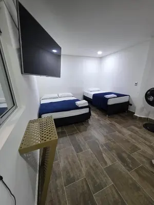 a room with two beds and a flat screen tv at Hotel Prestige in Medellín