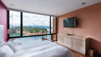 a bedroom with a large bed and a large window at Luxé Cabañas in Guatapé