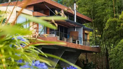 a house with a deck in the woods at Luxé Cabañas in Guatapé