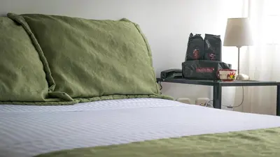 a bed with a green pillow on top of it at Hotel Portal de Milán in Manizales