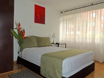 a bedroom with a bed with a vase of flowers on it at Hotel Portal de Milán in Manizales