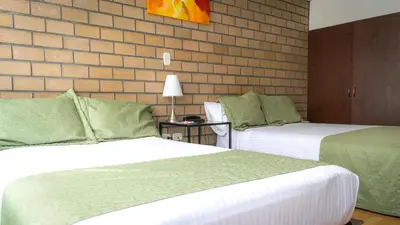 a hotel room with two beds and a brick wall at Hotel Portal de Milán in Manizales