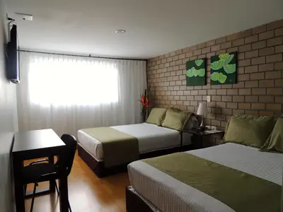 a hotel room with two beds and a window at Hotel Portal de Milán in Manizales