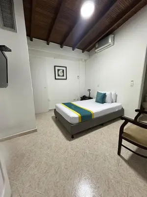 a bedroom with a bed and a chair in it at Hotel Lukas in Medellín