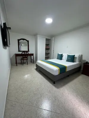 a bedroom with a bed and a table and a mirror at Hotel Lukas in Medellín