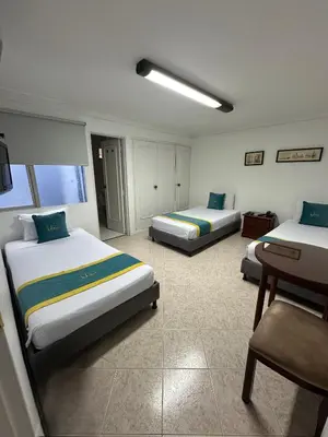 a hotel room with two beds and a chair at Hotel Lukas in Medellín