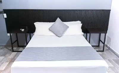 a white bed with two nightstands and two pillows at Hotel Palmas del Estadio in Medellín