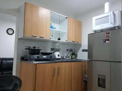 a kitchen with wooden cabinets and a stainless steel refrigerator at New Cozy Apartment in the Poblado, San Lucas in Medellín
