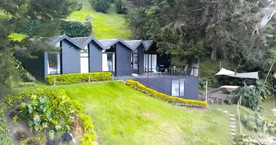 a house on the side of a hill with a yard at Cottage on the Lake - Cabaña privada - Guatapé - Jacuzzi in Guatapé