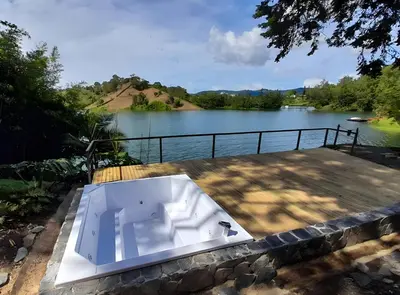 a bath tub sitting on a deck next to a lake at Cottage on the Lake - Cabaña privada - Guatapé - Jacuzzi in Guatapé