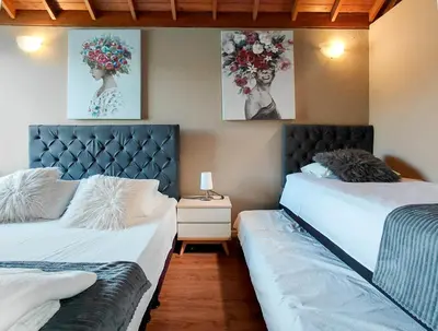two beds in a room with paintings on the wall at Cottage on the Lake - Cabaña privada - Guatapé - Jacuzzi in Guatapé