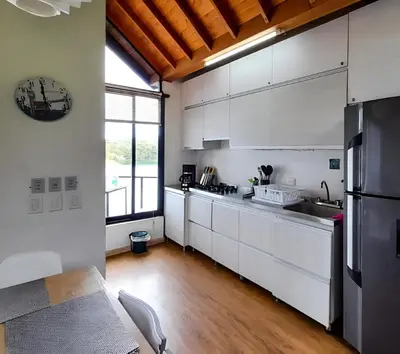 a kitchen with white cabinets and a large window at Cottage on the Lake - Cabaña privada - Guatapé - Jacuzzi in Guatapé