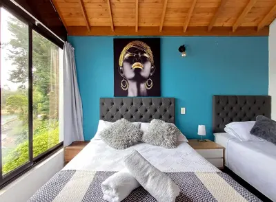 a bedroom with blue walls and a bed with pillows at Cottage on the Lake - Cabaña privada - Guatapé - Jacuzzi in Guatapé