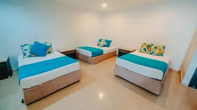 a room with three beds with blue pillows at La Iguana de Santa Fe by Bernalo Hotels in Santa Fe de Antioquia