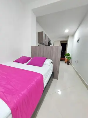 a bedroom with a large bed with a pink blanket at Apartaestudio Centro Comercial la Central in Medellín