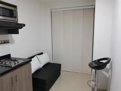 a small living room with a couch and a microwave at Apartaestudio Centro Comercial la Central in Medellín