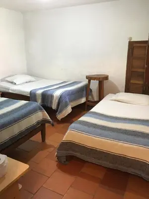 a room with two beds and a table at Selvablanca Hostel in San Jerónimo