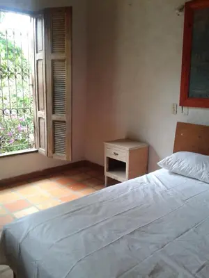 a bedroom with a white bed and a window at Selvablanca Hostel in San Jerónimo