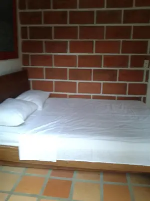 a bed in front of a brick wall at Selvablanca Hostel in San Jerónimo