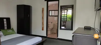 a bedroom with a bed and a bathroom with a toilet at Hotel Premium Real in Medellín