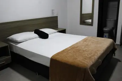 a bedroom with a large bed with a brown blanket on it at Hotel America 52 in Rionegro