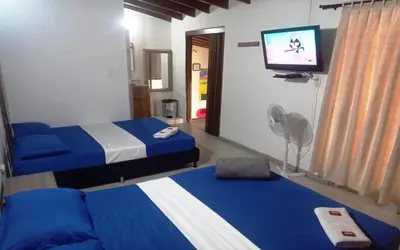 a room with two beds and a flat screen tv at Yellow House Hostel in Medellín