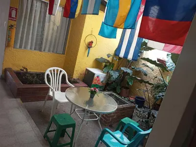 a patio with a table and chairs and flags at Yellow House Hostel in Medellín