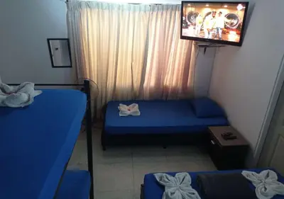 a room with two beds and a flat screen tv at Yellow House Hostel in Medellín
