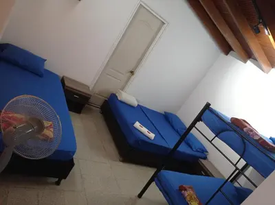 a bedroom with two beds with a fan and a door at Yellow House Hostel in Medellín