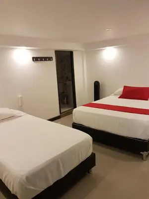 a hotel room with two beds with red sheets at Hotel Orion in Chinchiná