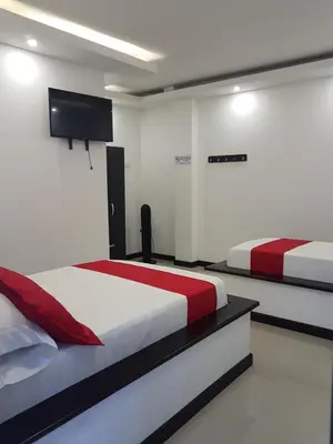 a bedroom with two beds and a flat screen tv at Hotel Orion in Chinchiná