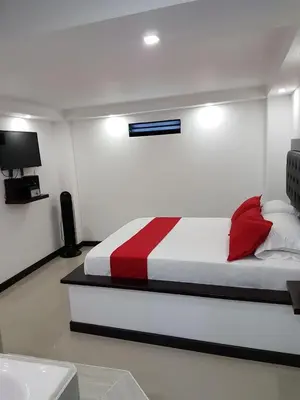 a bedroom with a bed with a red and white blanket at Hotel Orion in Chinchiná