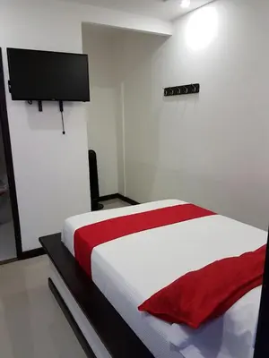 a bedroom with a white bed with a red blanket at Hotel Orion in Chinchiná