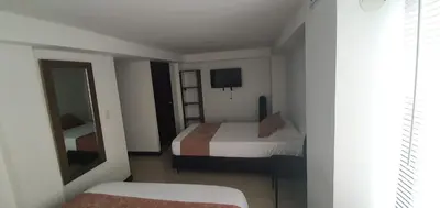 a hotel room with two beds and a mirror at Hotel Orion in Chinchiná