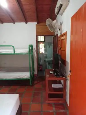 a room with two bunk beds and a desk with a television at Las Cabanas de Pino Hostel in Santa Fe de Antioquia