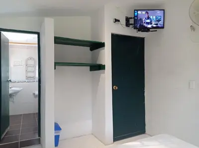 a bathroom with a tv on the wall and a door at Las Cabanas de Pino Hostel in Santa Fe de Antioquia