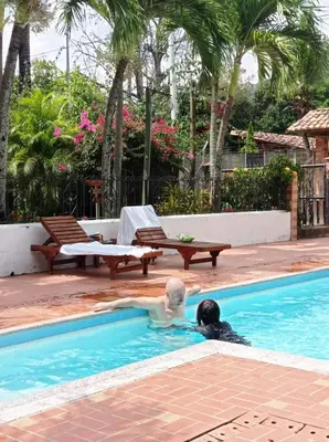 two people are swimming in a swimming pool at Las Cabanas de Pino Hostel in Santa Fe de Antioquia