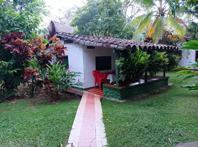 a small white house with a red chair in a yard at Las Cabanas de Pino Hostel in Santa Fe de Antioquia