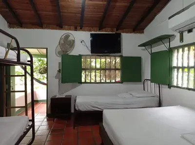 a room with two beds and a flat screen tv at Las Cabanas de Pino Hostel in Santa Fe de Antioquia
