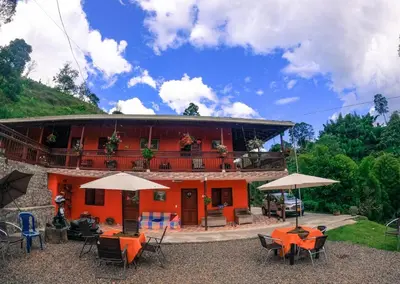 a building with tables and umbrellas in front of it at Hotel Orillas del Pizano in Jardin