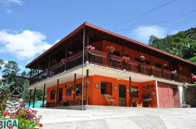 an orange house with a balcony and some flowers at Hotel Orillas del Pizano in Jardin