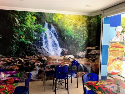 a dining room with a waterfall mural on the wall at Casa Hotel Manco Mora in Medellín