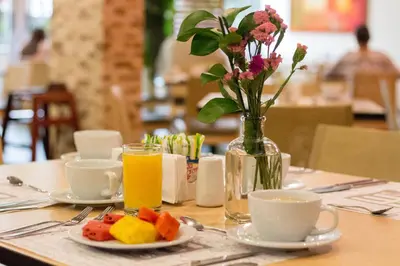 a table with a vase of flowers and a plate of fruit at Novelty Suites Hotel - Oviedo Mall in Medellín