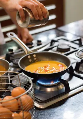 a person cooking a bowl of soup in a pan on a stove at Novelty Suites Hotel - Oviedo Mall in Medellín