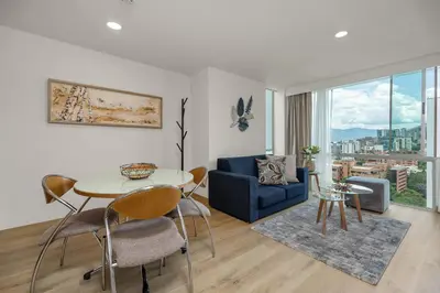 a living room with a table and a blue couch at Novelty Suites Hotel - Oviedo Mall in Medellín