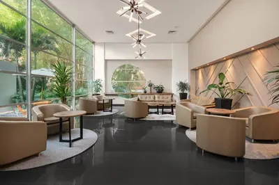a lobby with chairs and tables and windows at Novelty Suites Hotel - Oviedo Mall in Medellín